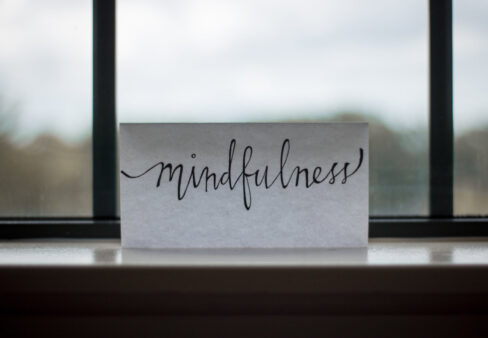 foglio di carta con scritto mindfulness appoggiato ad una finestra